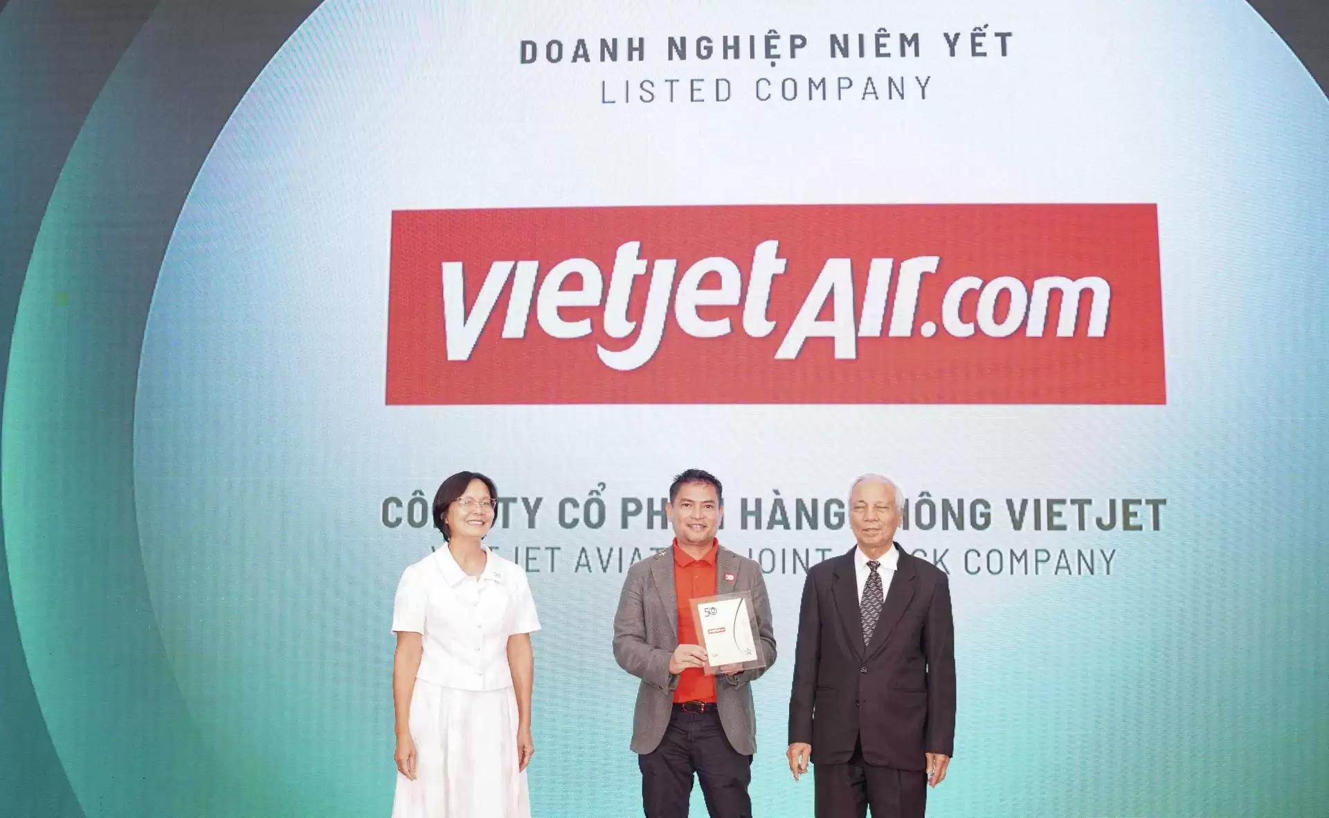 Ông Nguyễn An Di - Giám đốc Nhân sự Vietjet (áo T - shirt đỏ, áo khoác ghi xám) nhận giải thưởng tôn vinh Top 50 doanh nghiệp phát triển bền vững từ ban tổ chức.